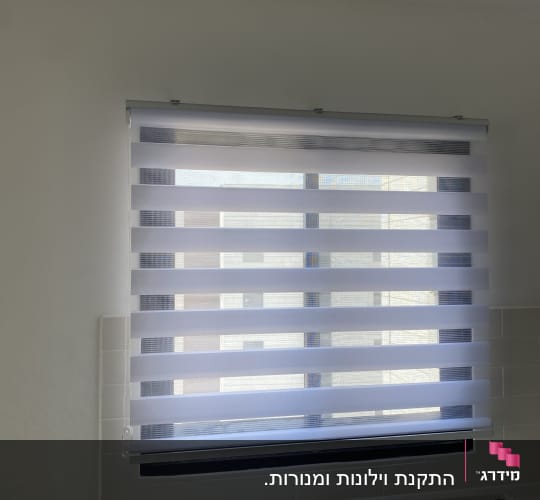 תריסים מותקנים על חלון בחדר מואר